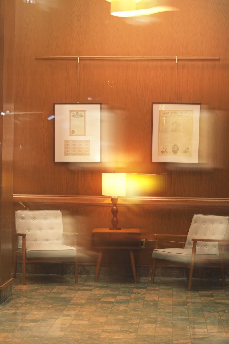 Warm wood-paneled hotel lobby with two armchairs and a glowing table lamp