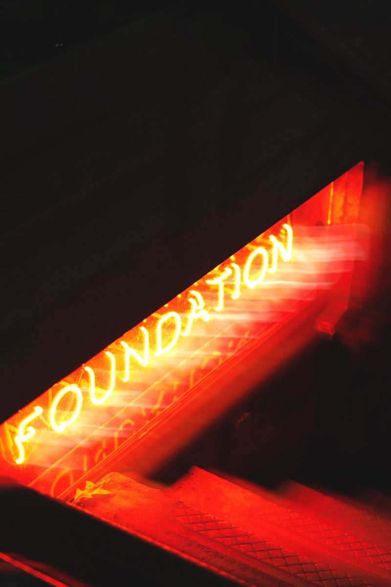 Red neon 'Foundation' sign glowing at night in Raleigh