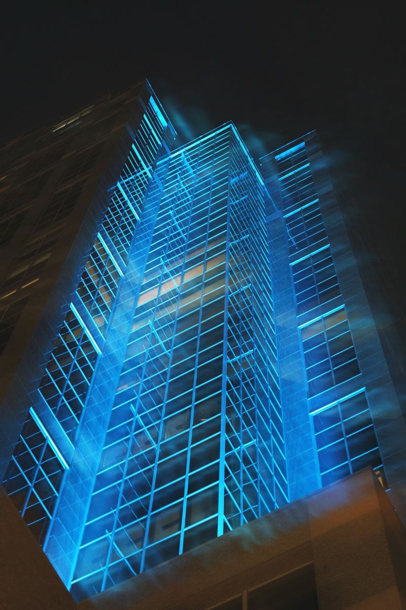 Downtown Raleigh skyscraper lit electric blue at night, viewed from below