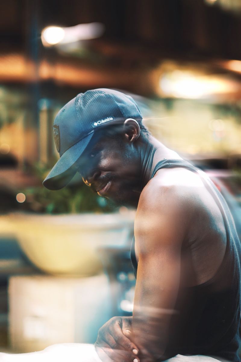 Candid night portrait of a man in a baseball cap under warm street lights in Raleigh