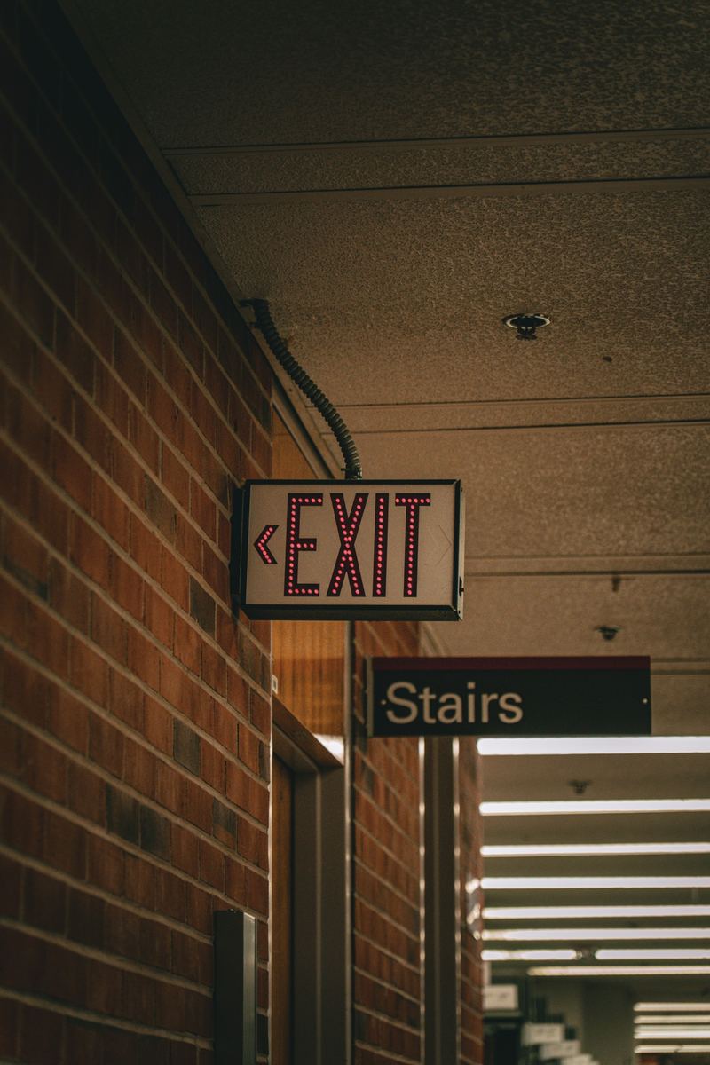 Vintage 'Exit' and 'Stairs' signs on a brick wall in a downtown interior