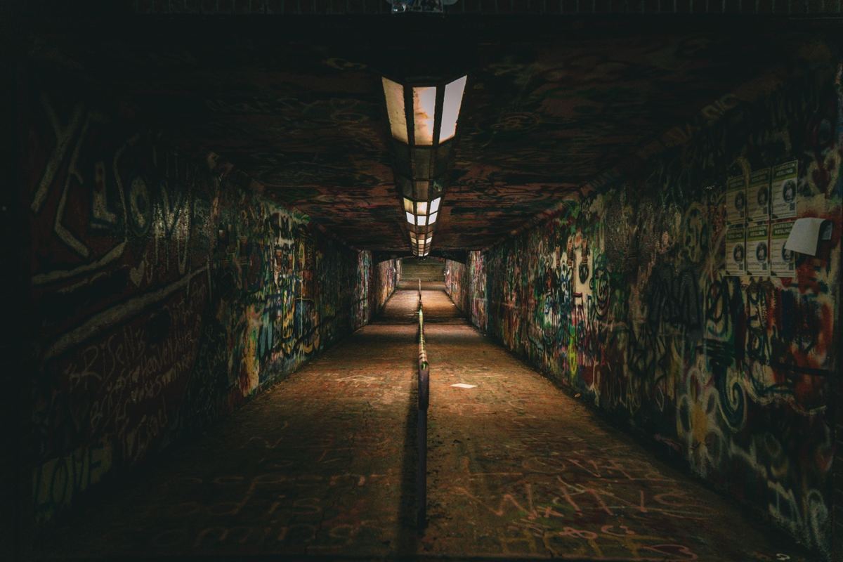 Graffiti-covered pedestrian tunnel glowing at night in Raleigh