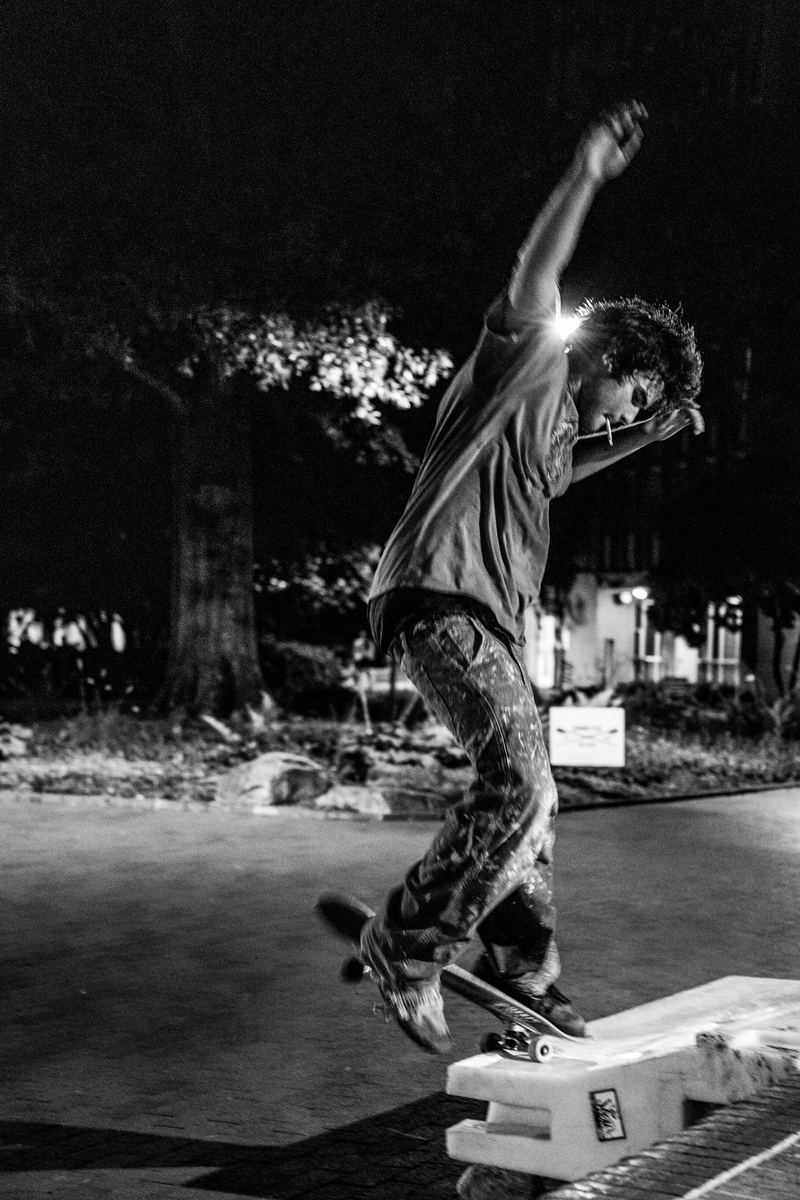 Black-and-white photo of a skateboarder landing a trick on a ledge at night in Raleigh