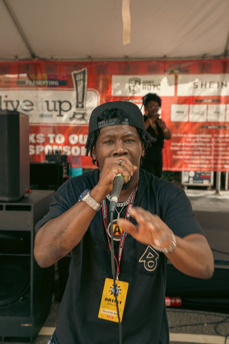Emcee speaking into a microphone on stage at an outdoor Raleigh event