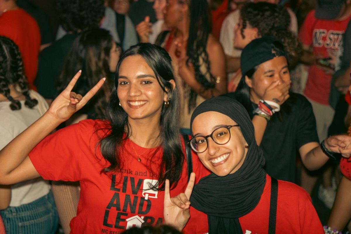 Excited crowd of young women posing at a nighttime outdoor concert in Raleigh