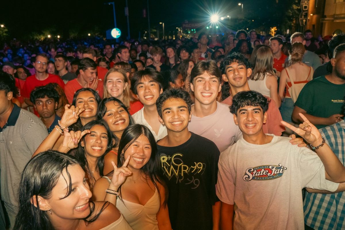Large group of friends posing together at a nighttime outdoor concert in Raleigh