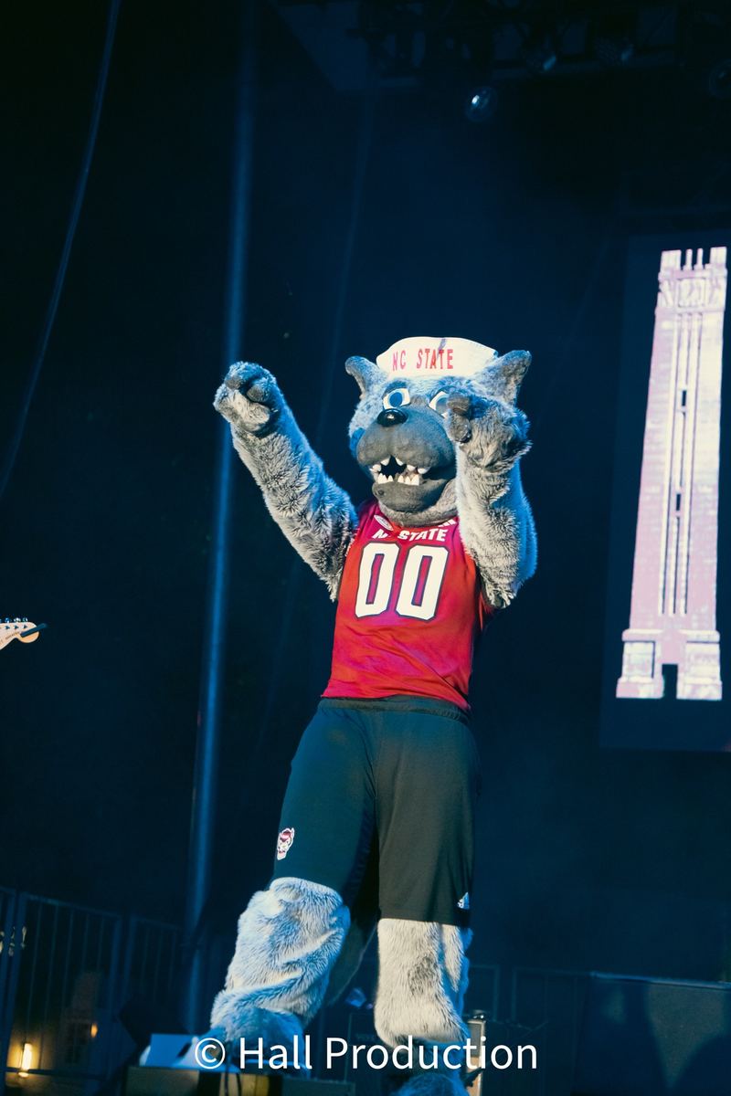 NC State Wolfpack mascot Mr. Wuf performing on stage at a Raleigh event