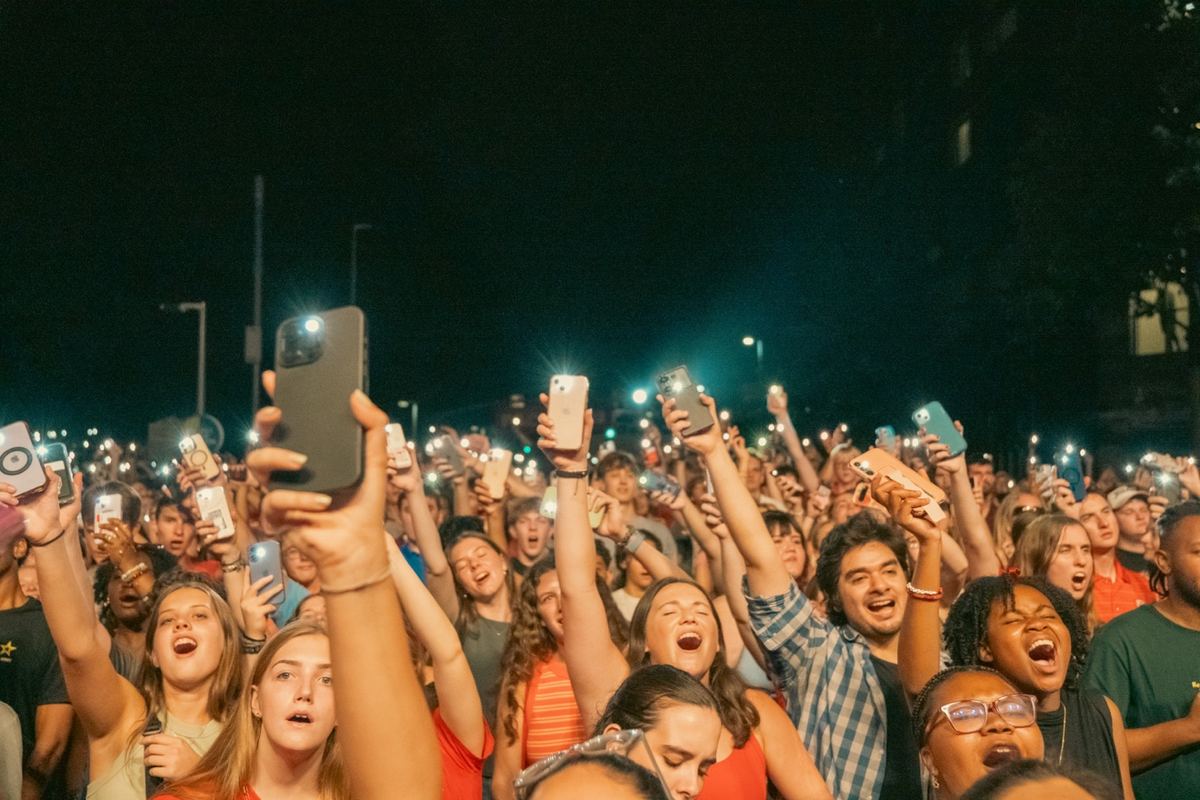 Concert crowd holding phones up to capture the show at night in Raleigh