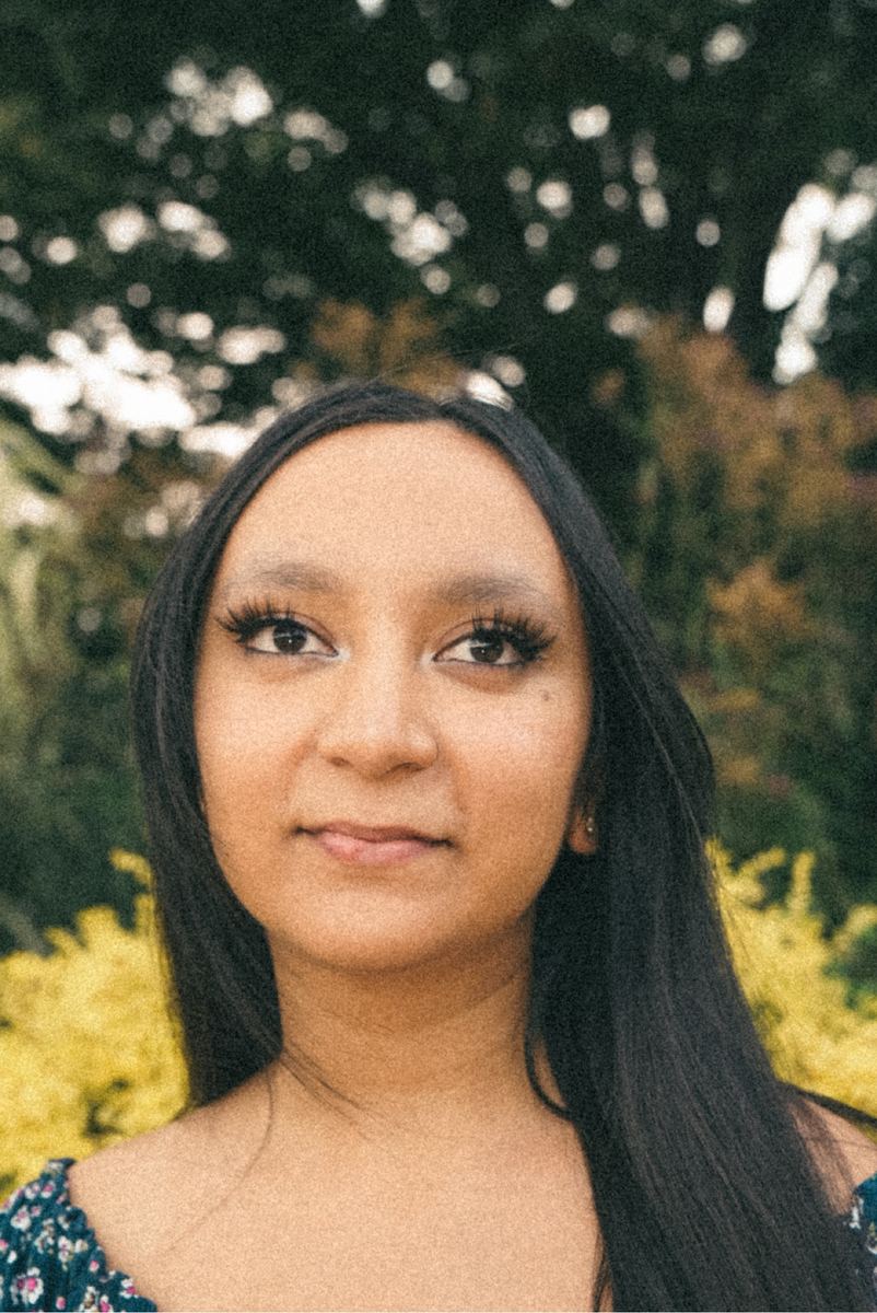 Outdoor portrait of a young woman with long dark hair against yellow spring blossoms in Raleigh