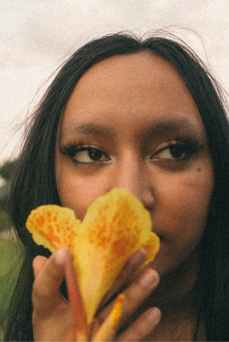 Close-up portrait of a young woman holding a yellow flower to her face