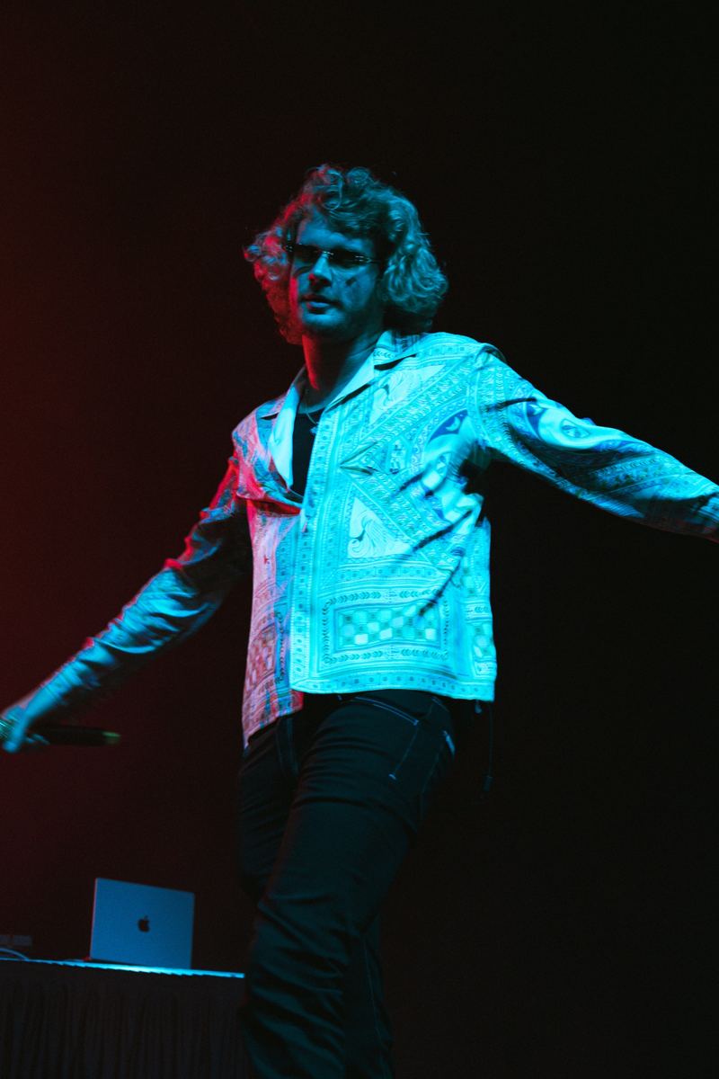 Musician performing on stage bathed in blue light at a Raleigh concert