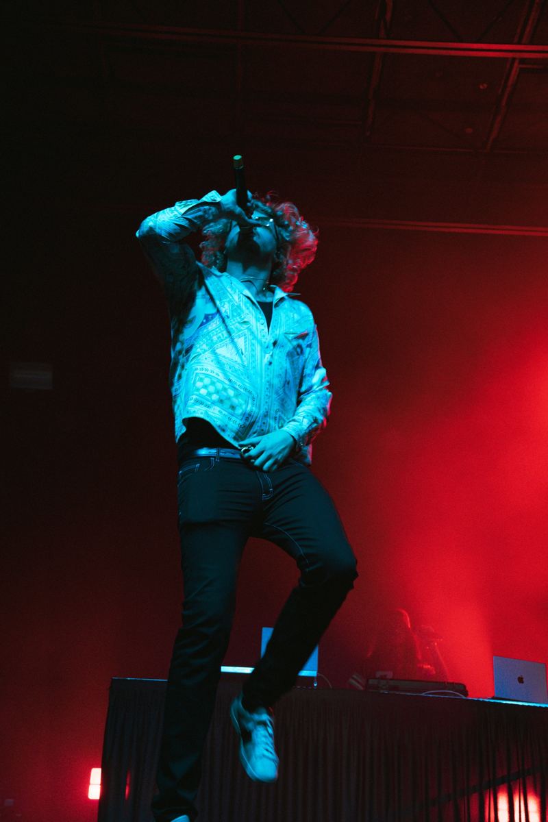 Singer performing under dramatic red stage lighting at a live concert